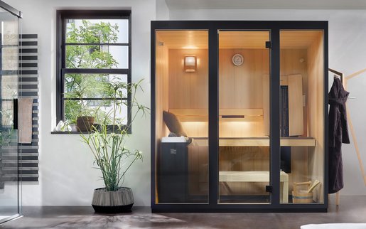 Moderne, kompakte Sauna EASY in Schwarz mit heller Holzverkleidung innen, Glasfront und integrierter Infrarot-Zusatzausstattung in einem Badezimmer.