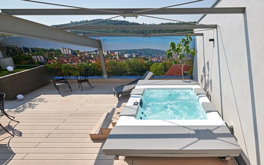 [Translate to Austria:] Auf der Terrasse im Whirlpool entspannen: Der von SSF.Pools by KLAFS installierte Whirlpool verfügt über verschiedenen Massagedüsen, Luftmassage und Licht.